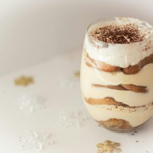 Close-up of a creamy tiramisu dessert in a glass, beautifully presented with cocoa topping, perfect for tasty indulgence.